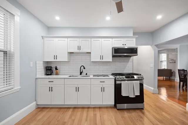 a kitchen with stainless steel appliances a sink stove and wooden floor