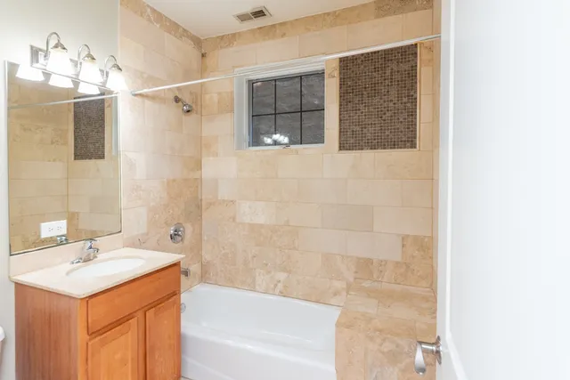 a bathroom with a granite countertop sink a mirror and a bathtub