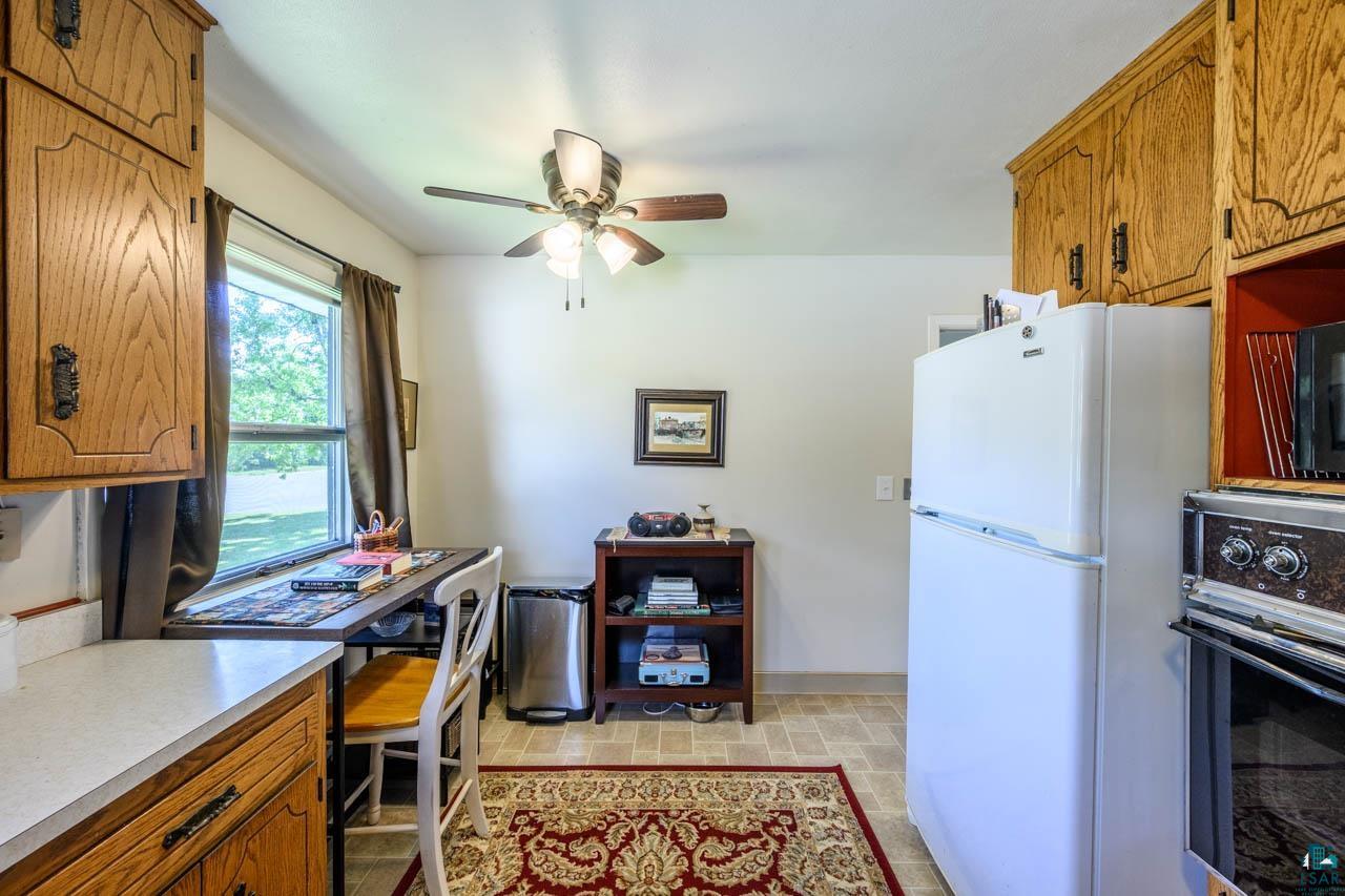 301 2nd Street North Biwabik, MN 55708 - Photo 10 of 43 Kitchen featuring wood cabinetry, light-toned countertops, tile-style flooring, a ceiling fan with integrated lighting, and a window providing natural illumination