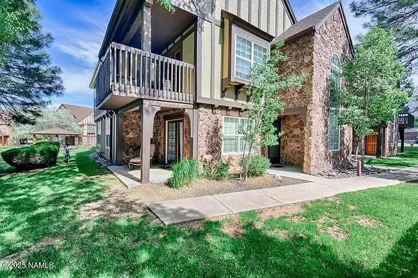 a view of a brick house with many windows plants and large tree