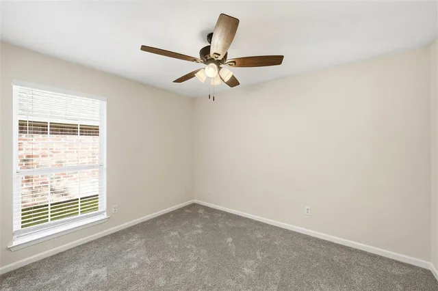 an empty room with a window and a ceiling fan