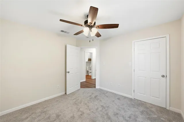 an empty room with closet and a ceiling fan