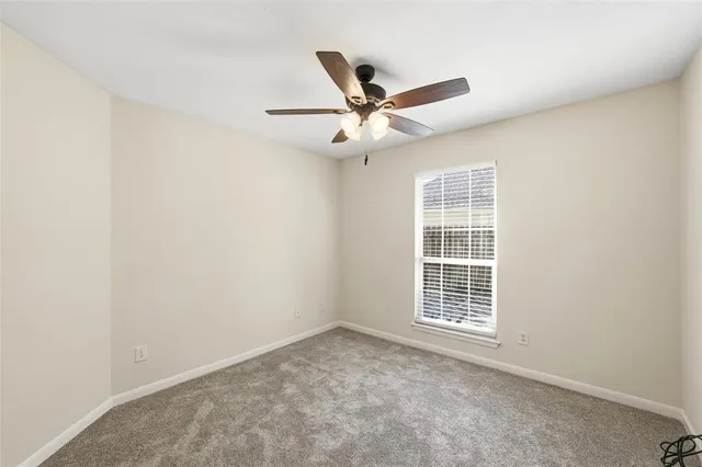 an empty room with ceiling fan and window