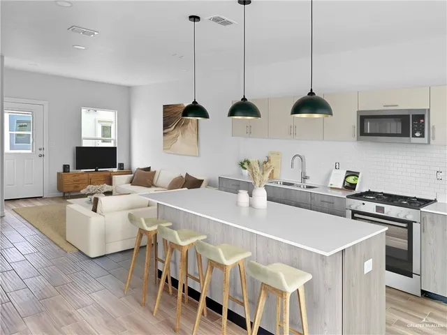 a kitchen with stainless steel appliances a stove a sink a microwave a dining table chairs and white cabinets