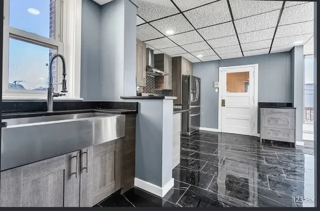 a kitchen with granite countertop a refrigerator and a stove top oven