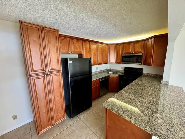 a kitchen with granite countertop stainless steel appliances a refrigerator and a sink