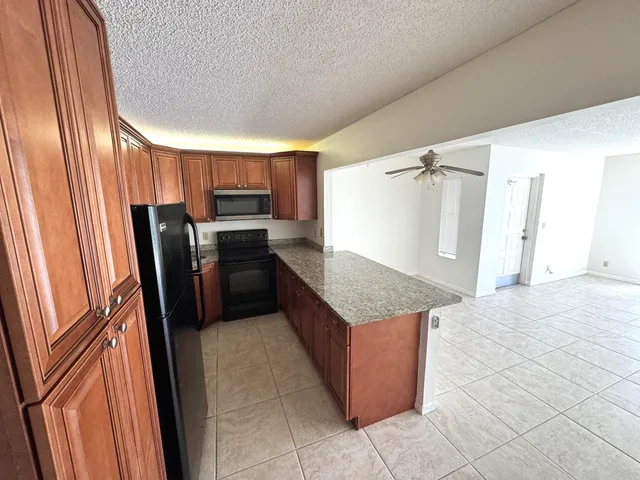 a kitchen with granite countertop a refrigerator and microwave