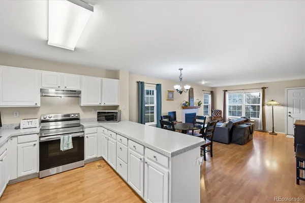 a kitchen with stainless steel appliances a stove top oven a sink a refrigerator and white cabinets