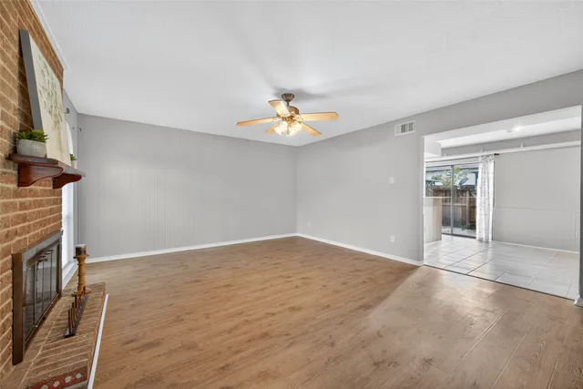 a view of an empty room with window and wooden floor