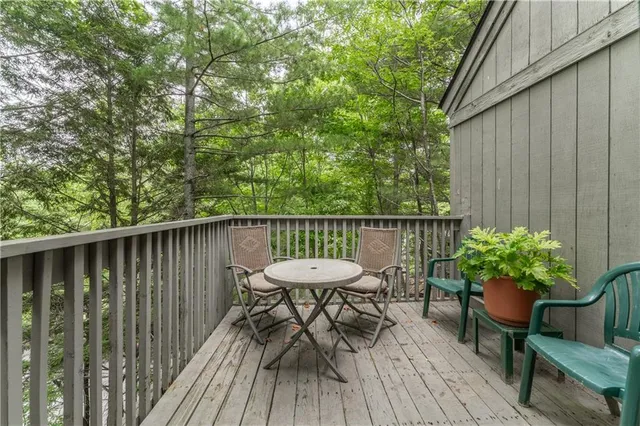 a balcony with wooden floor table and chairs