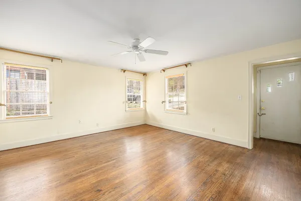 a view of an empty room with wooden floor and a window