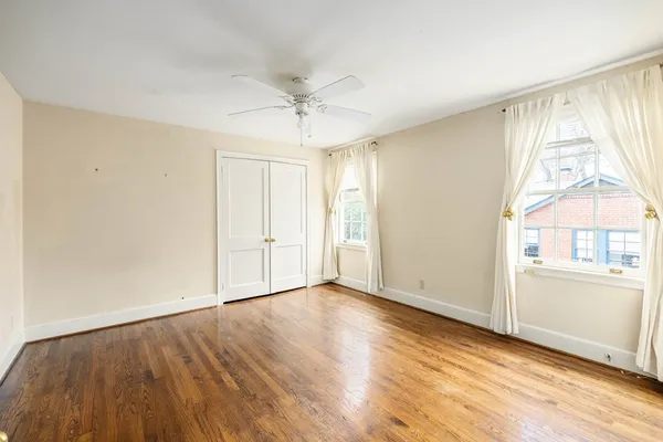 an empty room with wooden floor fan and windows