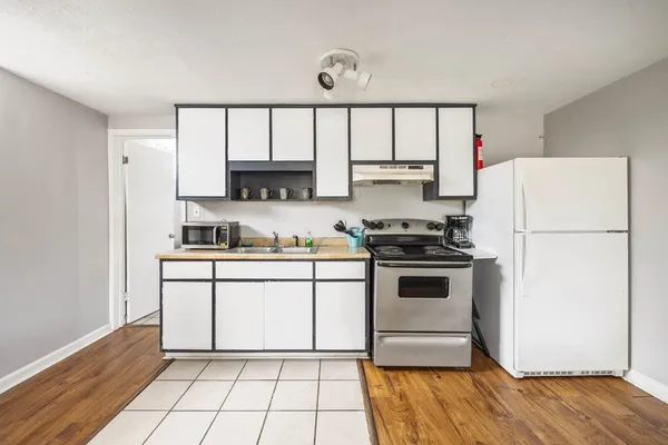 a kitchen with a refrigerator a stove top oven and white cabinets