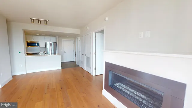 a view of kitchen and empty room with wooden floor