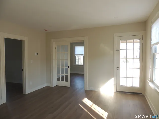a view of an empty room with wooden floor and a window