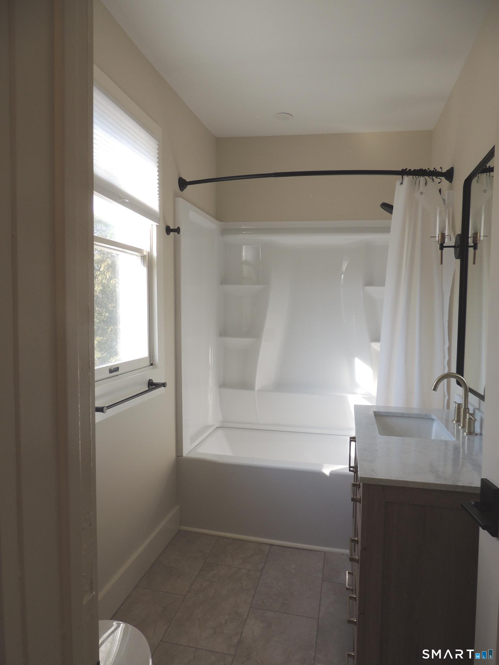 56-58 Harrison Avenue, Unit 2 Branford, CT 06405 - Photo 25 of 39 a bathroom with a shower sink and mirror