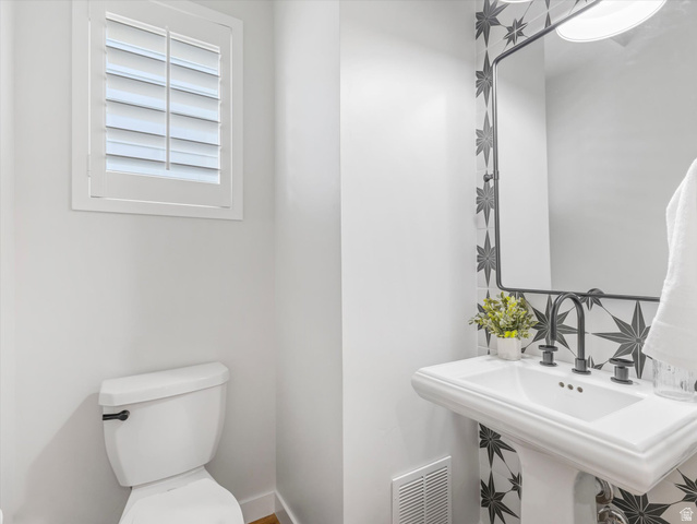 11759 South Watercourse Road South Jordan, UT 84009 - Photo 10 of 33 Modern powder room featuring a patterned tile accent wall, pedestal sink with matte black fixtures, rectangular mirror, and white plantation shutters