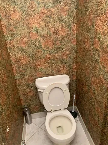 a toilet sitting in a bathroom next to a wooden wall