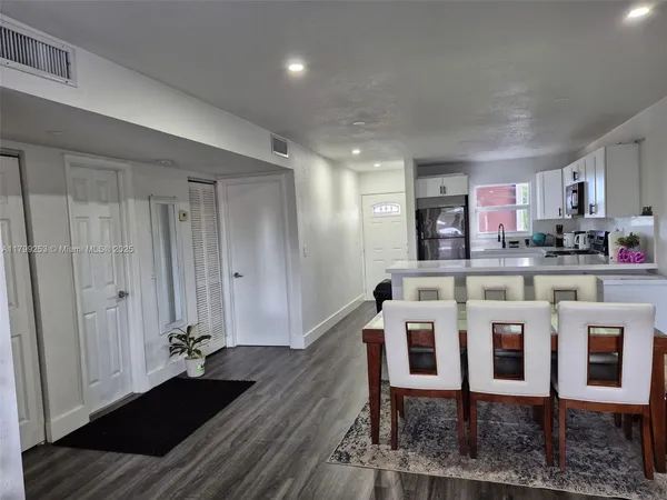 a kitchen with a dining table chairs and white cabinets
