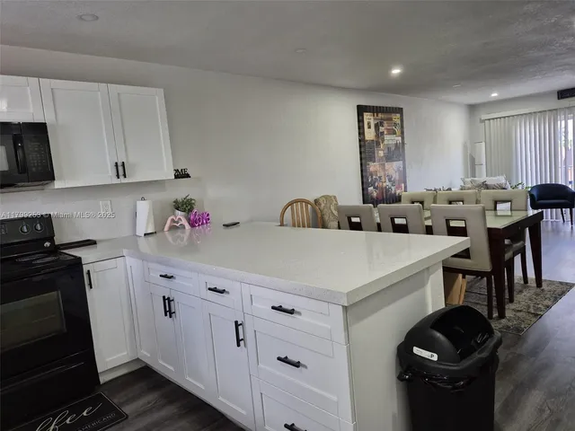 a kitchen with granite countertop a sink a stove and white cabinets
