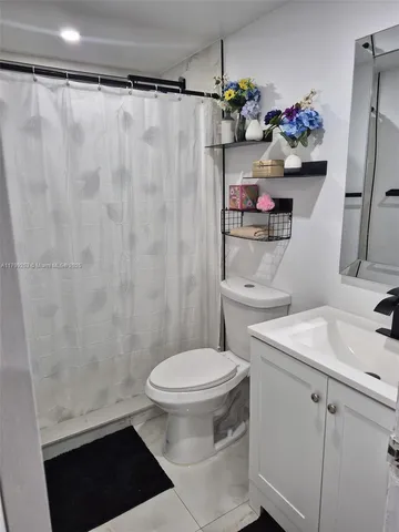 a bathroom with a sink a toilet and shower curtain