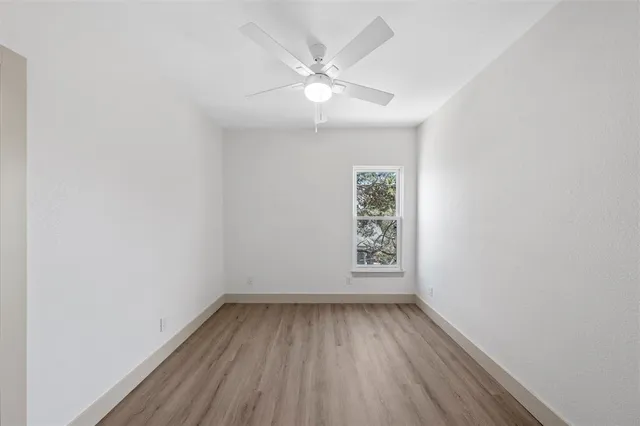 an empty room with a window and a fan