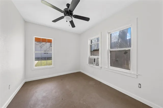 an empty room with a window and a ceiling fan