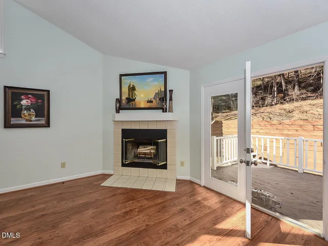 a view of an empty room with wooden floor and a fireplace