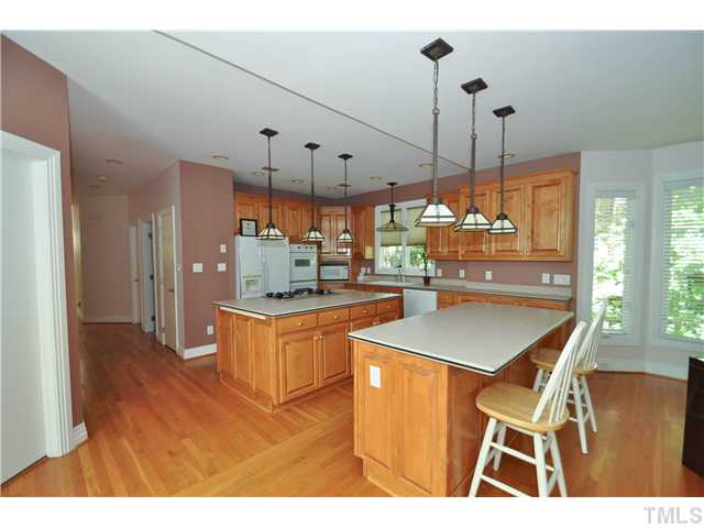 6424 Rushingbrook Drive Raleigh, NC 27612 - Photo 5 of 25 a kitchen with stainless steel appliances kitchen island granite countertop a table chairs and a refrigerator