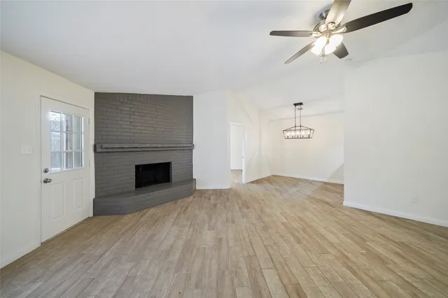 an empty room with wooden floor a ceiling fan and fireplace
