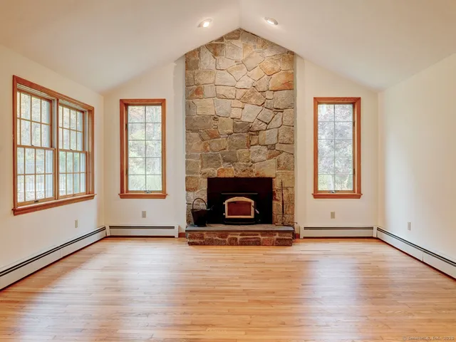 an empty room with windows a fireplace and wooden floor