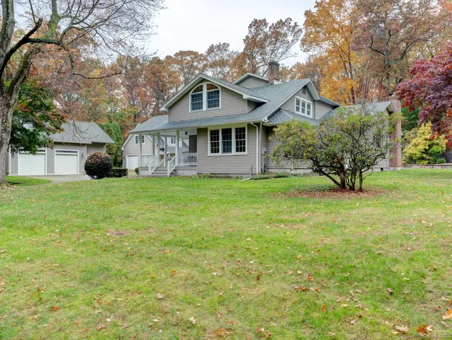 a view of a house next to a big yard and large trees