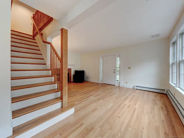 a view of an empty room with wooden floor and stairs