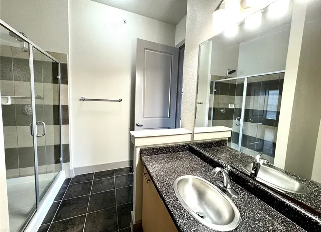 a bathroom with a granite countertop sink a mirror and a shower