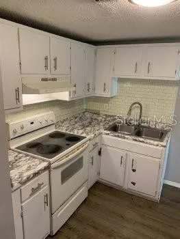 a white kitchen with sink and cabinets
