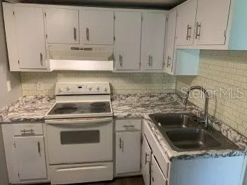 a kitchen with granite countertop white cabinets and white appliances