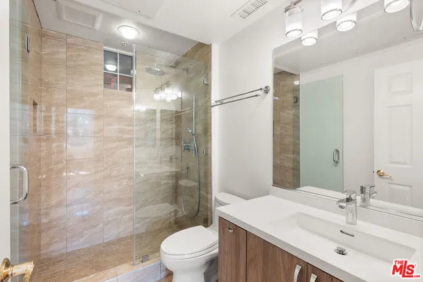 a bathroom with a sink a toilet a mirror and shower