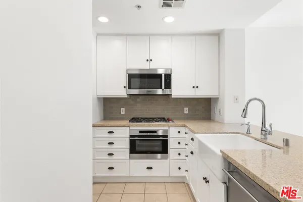 a kitchen with granite countertop a stove a sink and a microwave