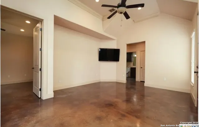 a view of an empty room with a fan and a kitchen