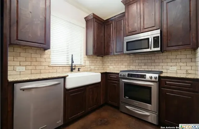 a kitchen with stainless steel appliances granite countertop a sink stove and microwave