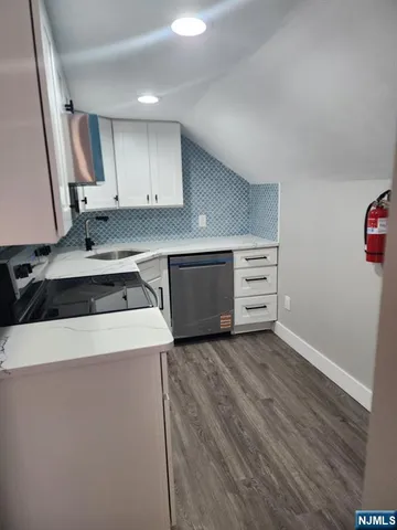 a kitchen with cabinets appliances and wooden floor