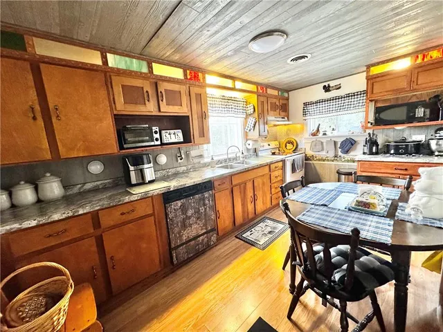 a kitchen with stainless steel appliances granite countertop a stove a sink dishwasher and cabinets with wooden floor