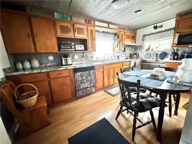 a kitchen with granite countertop a table chairs stove top oven and cabinets