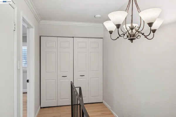 a view of a hallway with wooden floor and chandelier