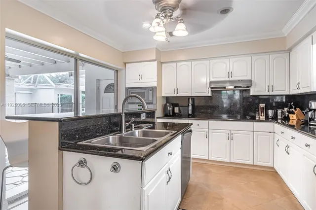 a kitchen with granite countertop a sink stainless steel appliances and white cabinets