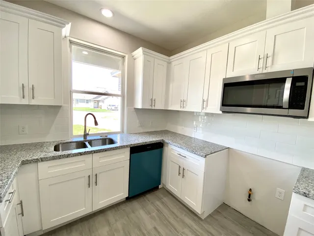 a kitchen with stainless steel appliances granite countertop a sink a stove and microwave with wooden floor