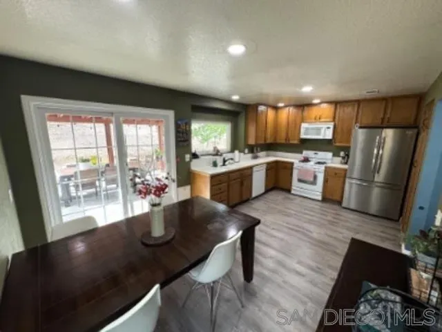 a kitchen with stainless steel appliances granite countertop sink refrigerator dining table and chairs