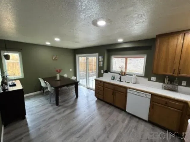 a large living room with kitchen island granite countertop furniture a sink a window and wooden floor