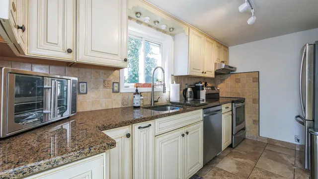 a kitchen with granite countertop a sink stainless steel appliances and cabinets