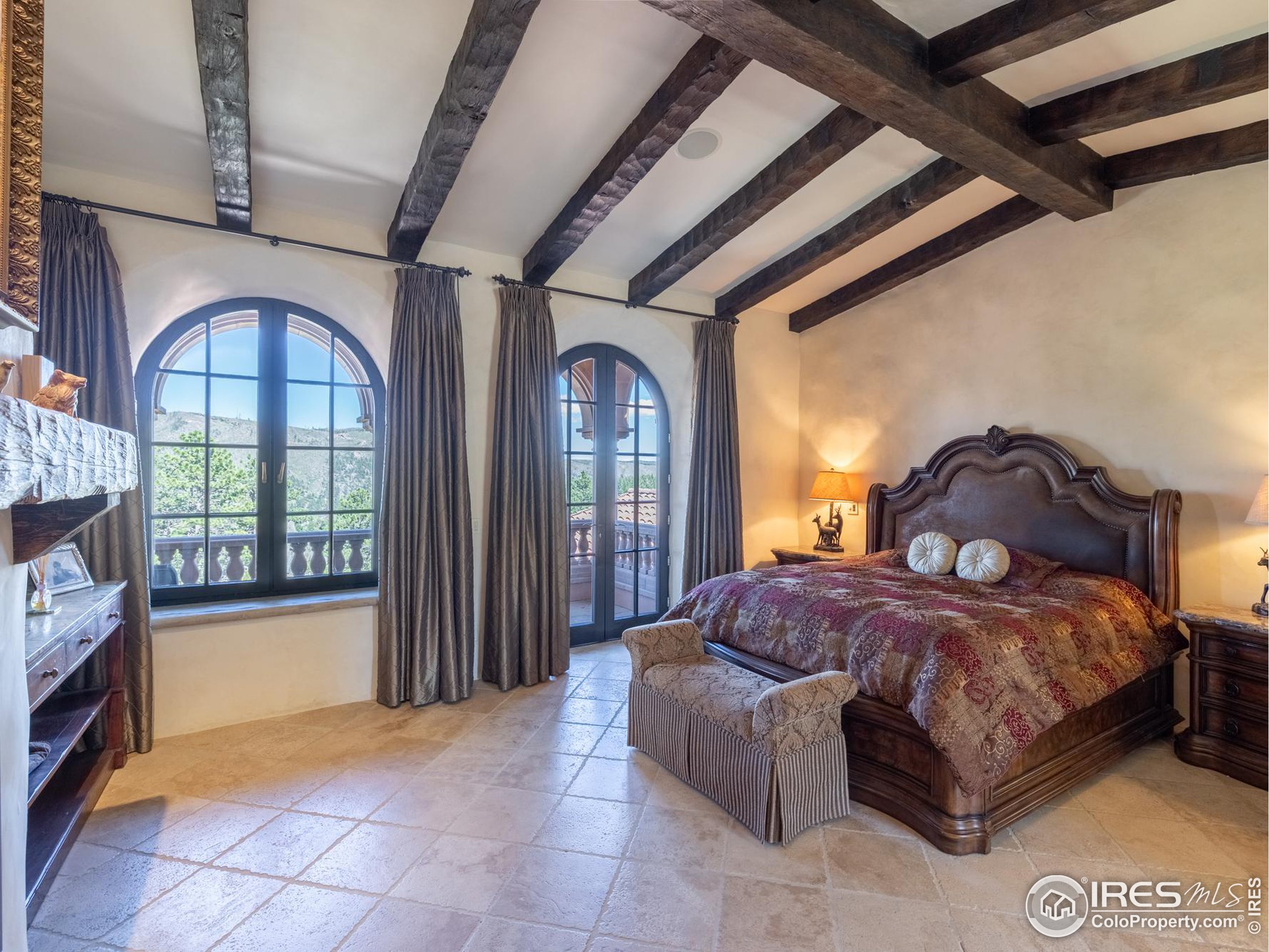 9200 Old Flowers Road Bellvue, CO 80512 - Photo 29 of 50 a spacious bedroom with a bed a fireplace and a large window